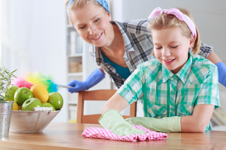 Girl wiping a table and her mum watching her