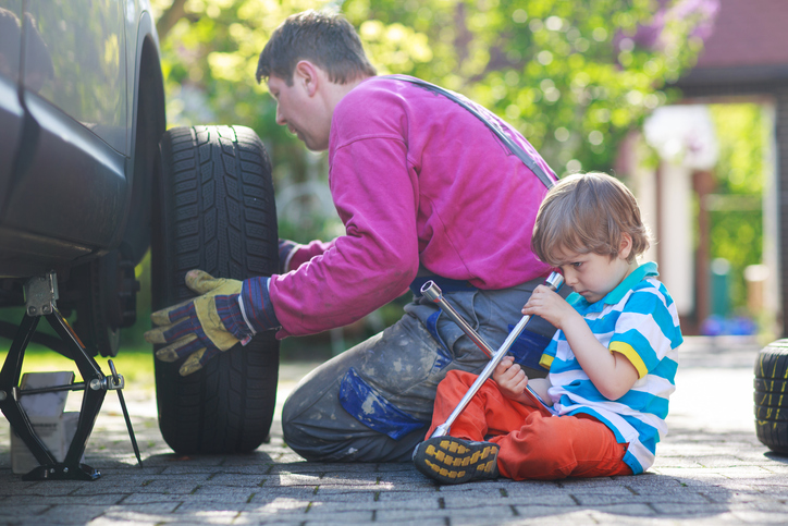Father with little boy repairing and changing wheel