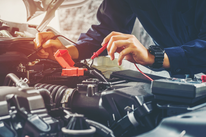 Auto mechanic checking car battery voltage