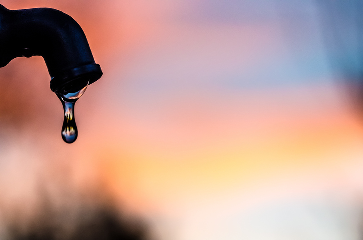 Drop of water coming out of a metal tap