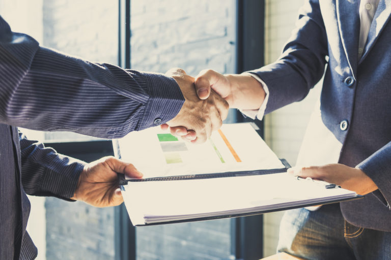 Business partnership meeting concept. Successful businessmen handshaking after good deal and hold financial file. Group support concept.