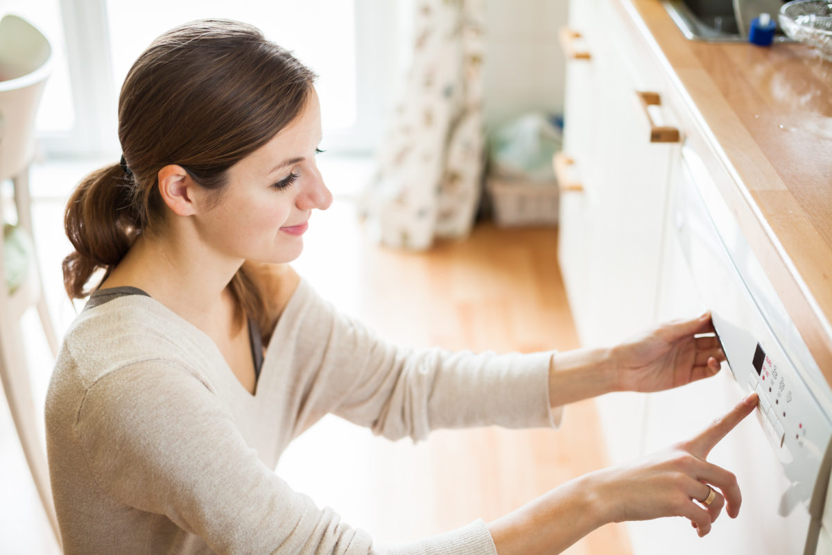 Housework: young woman putting dishes in the dishwasher