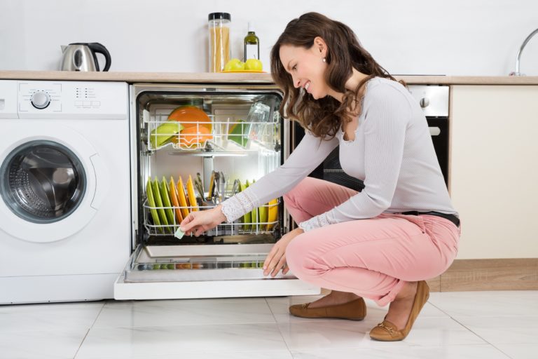 Woman Putting Detergent Tablet In Dishwasher