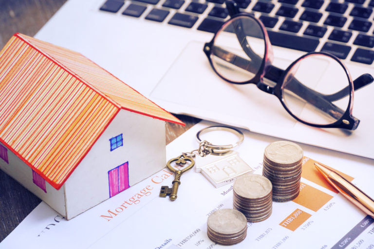 Key with pen and house model and glasses on notebook lay on mortage document,finance concept.