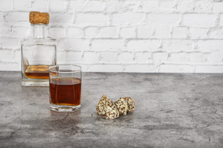 A glass of brandy or whiskey on a background of gray stone with truffles. Place for text