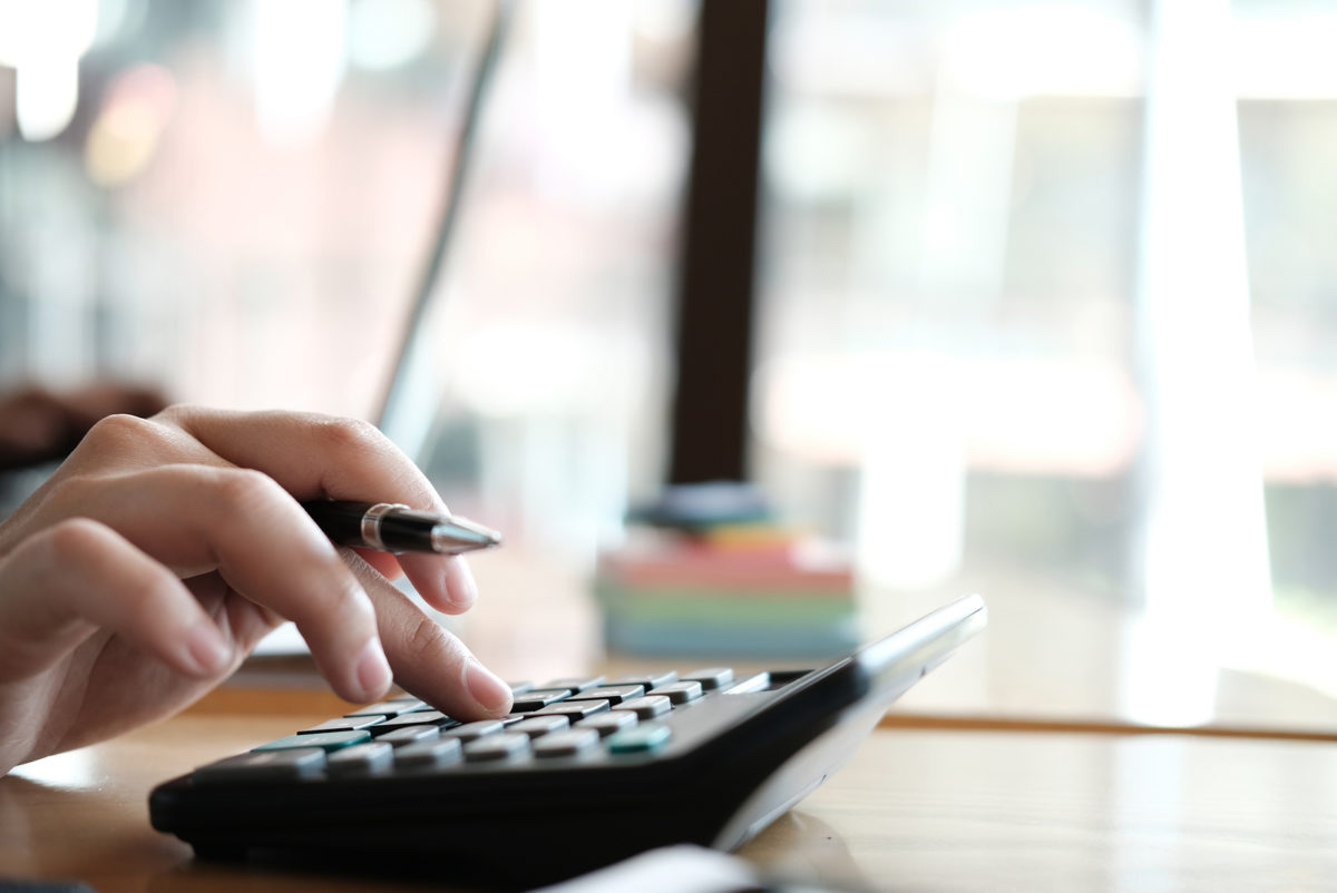 Financial Adviser Working With Calculator &amp; Computer At Office.