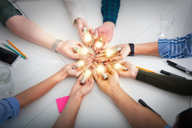 Teamwork and brainstorming concept with businessmen that share an idea with a lamp. Concept of startup