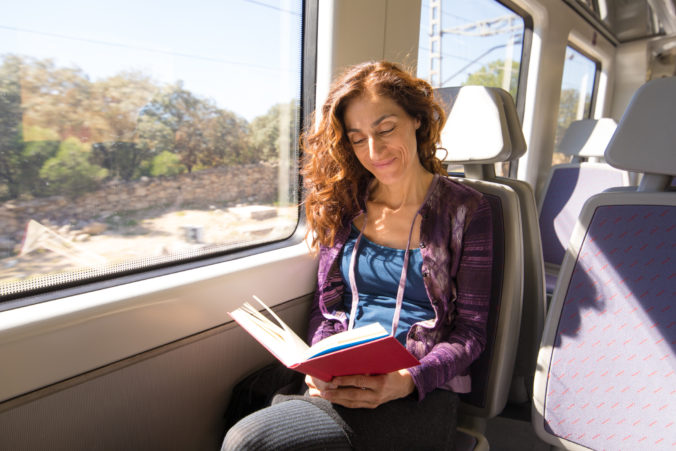 Happy woman in train reading book
