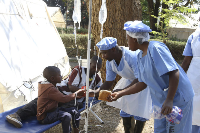 Zdravotníci ponúkajú jedlo otcovi so synom, ktorých liečia na choleru v Zimbabwe.