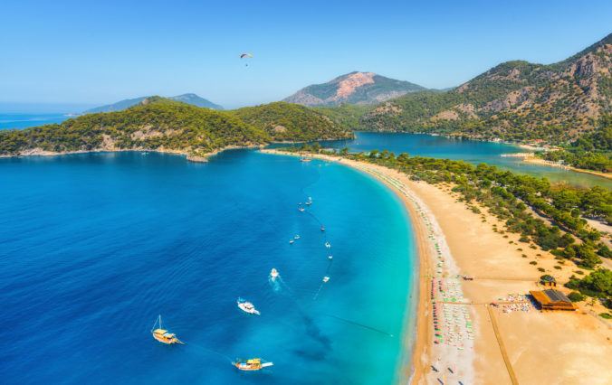 Amazing aerial view of Blue Lagoon in Oludeniz, Turkey. Summer landscape with sea spit, boats and yachts, green trees, azure water, sandy beach in sunny day. Travel. Top view of national park. Nature