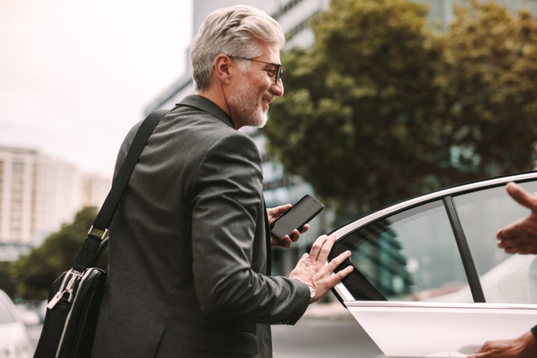 Happy mature commuter getting into a taxi