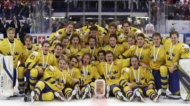 Rasmus Sandin, left, and Sweden's goaltender Hugo Alnefelt, center, make a save against Finland's Ville Petman