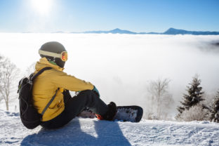 Snowboarder sitting and looking at mountain chain