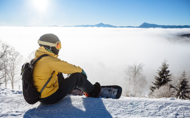 Snowboarder sitting and looking at mountain chain
