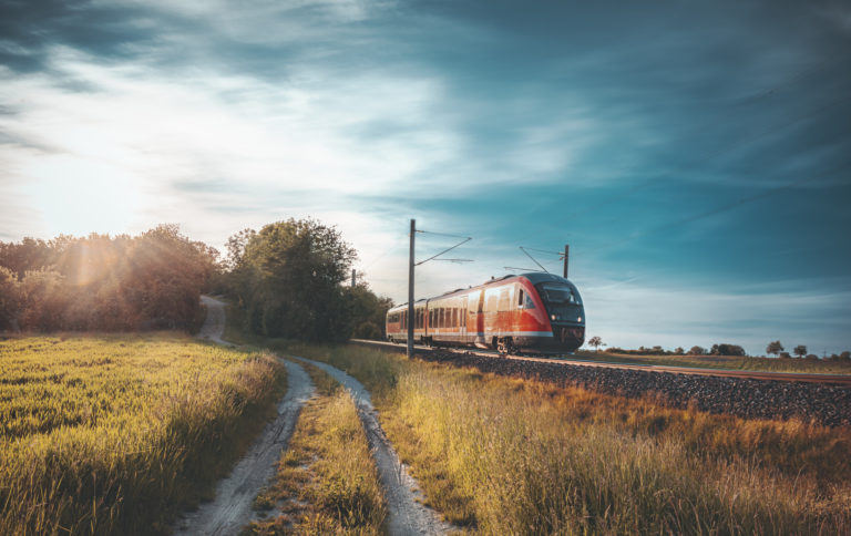 Red German train traveling on railway tracks through nature
