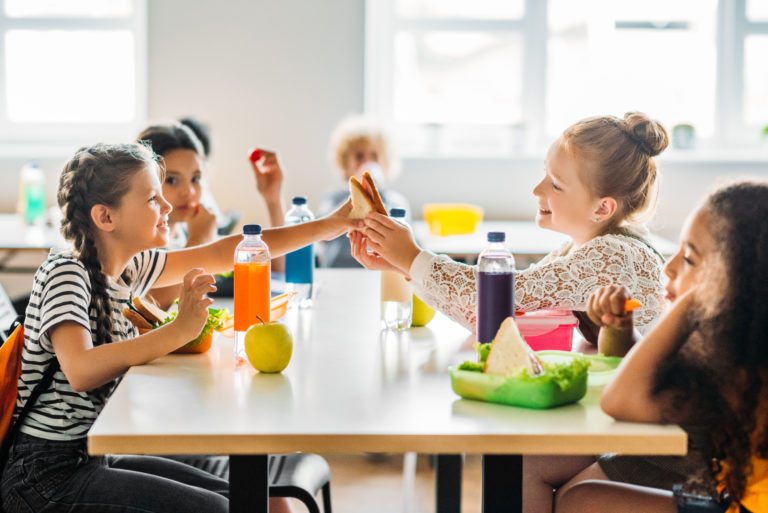 Adorable schoolgirls taking lunch at school cafeteria