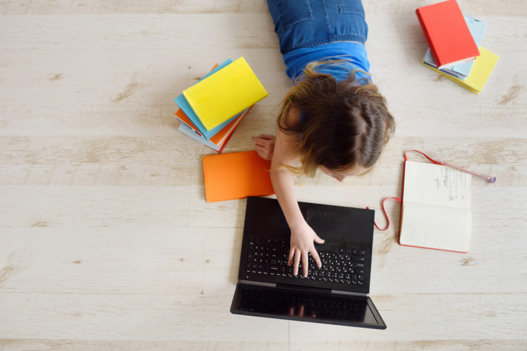 Teenage girl uses a laptop. Online education, home schooling. Communication on the Internet, chats.