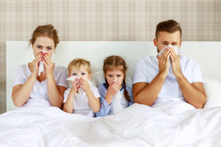 Colds and viral diseases. family with runny nose and fever in bed