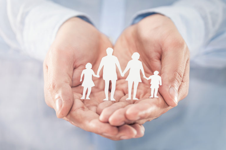 Family care concept. Hands with paper silhouette on table.