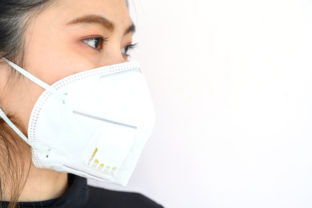 Close up of young Asian woman wearing N95 mask for protect smog PM2.5 bad air pollution.