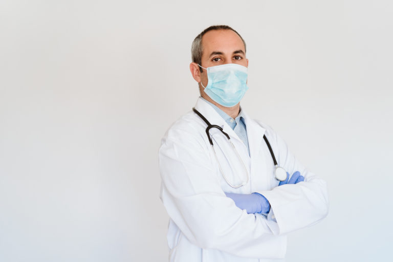 Portrait of middle age doctor wearing protective mask and gloves indoors. Corona virus concept