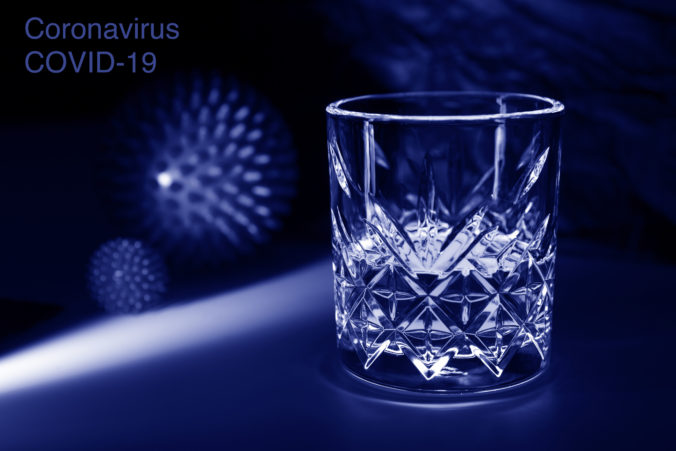 Blue glass with alcohol. Concept - protection against a pandemic or viral infection with strong alcoholic beverages. Whiskey, brandy, brandy, tequila, vodka can be used as disinfectant liquids. Text