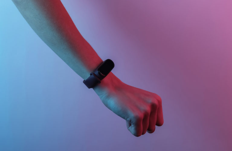 Female hand with a smart bracelet. Modern gadgets. Creative pop art pink blue neon color. Trendy gradient illumination. Night light