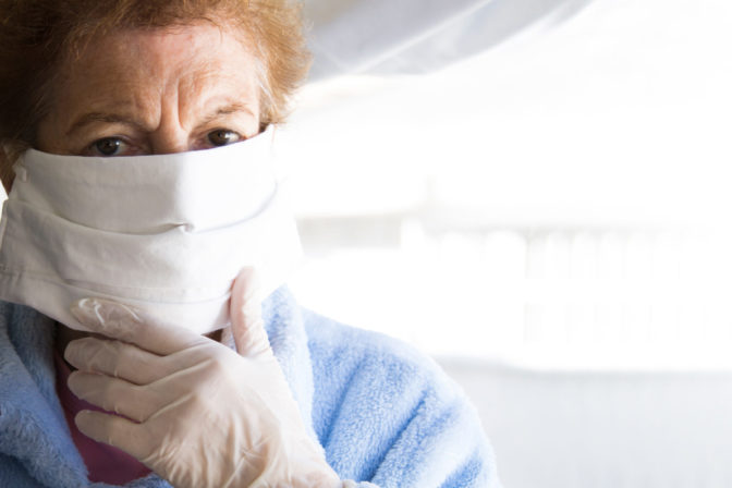 Senior woman using mobile phone with mask and disposable medical gloves. Safety measures during the coronavirus outbreak