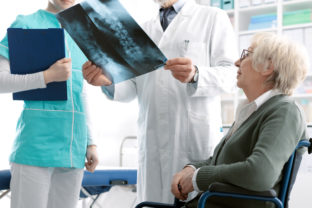 Doctor checking a senior female patient's x ray image during a visit at the hospital, injury and osteoporosis concept