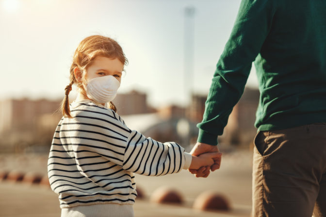Little girl in medical mask holding hand of father