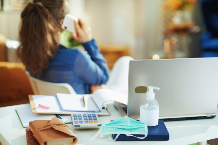 Medical mask and hand disinfectant and woman talking on phone