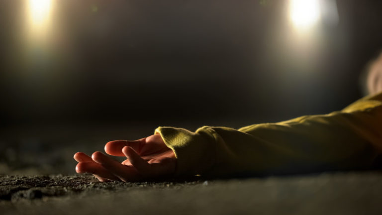 Bloody female victim of deadly car accident lying on road, close up view at body