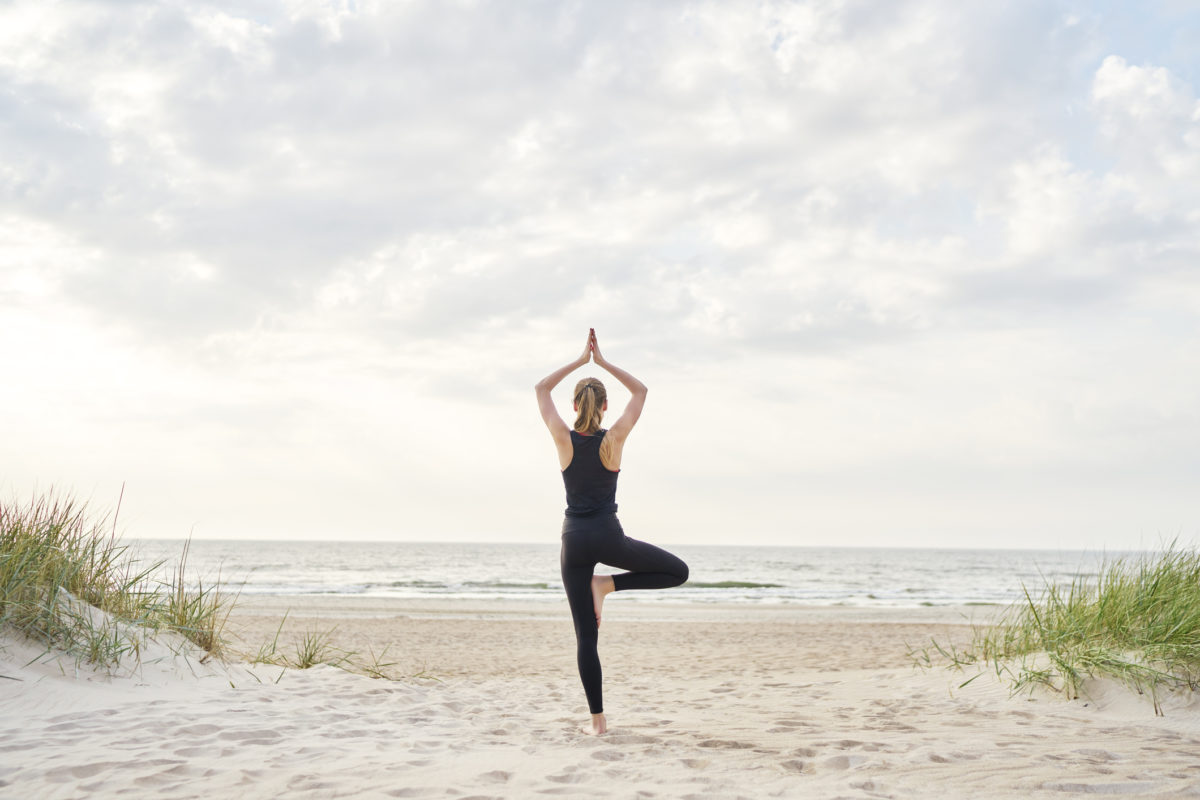Young woman doing yoga on the beach