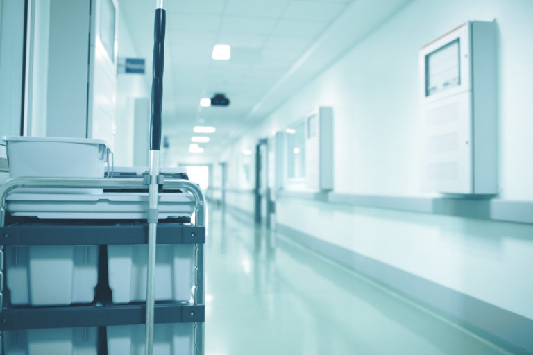 Cleaning staff cart with disinfectant solution containers in the empty hospitall hall
