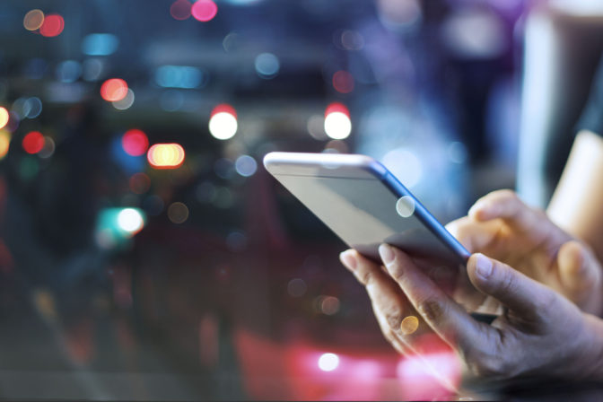 Woman using mobile smart phone in the night light colorful background