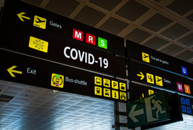 Information panel with Covid 19 word on it at an international airport.
