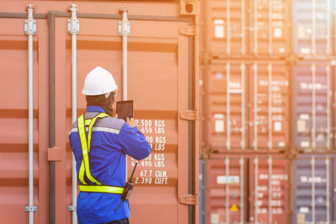 Foreman control loading Containers box from Cargo freight ship by tablet,Freight shipping containers at the docks,Large container shipping at shipping yard main transportation of cargo container.