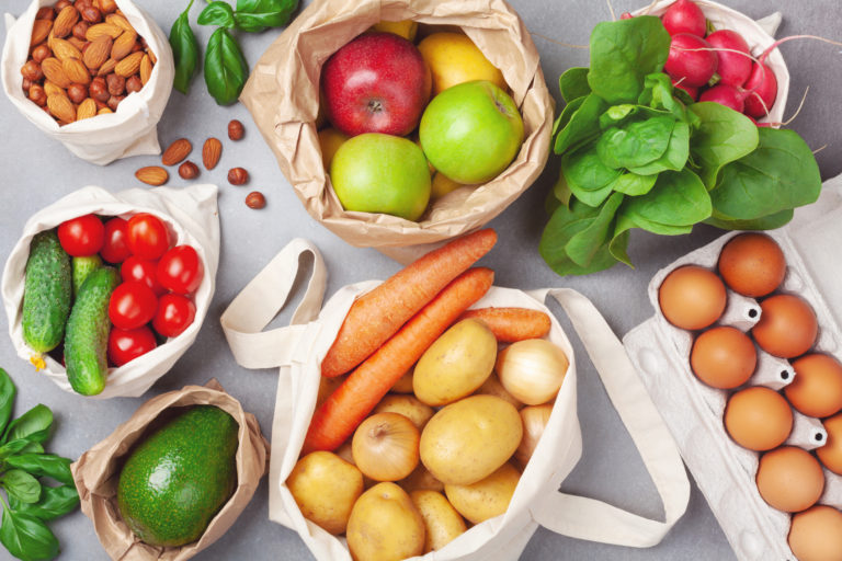 Zero waste and eco friendly shopping with vegetables and fruits in textile and paper bags top view. Plastic free and reuse concept.