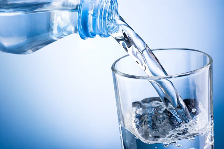 Closeup of bottle of water pouring into a glass