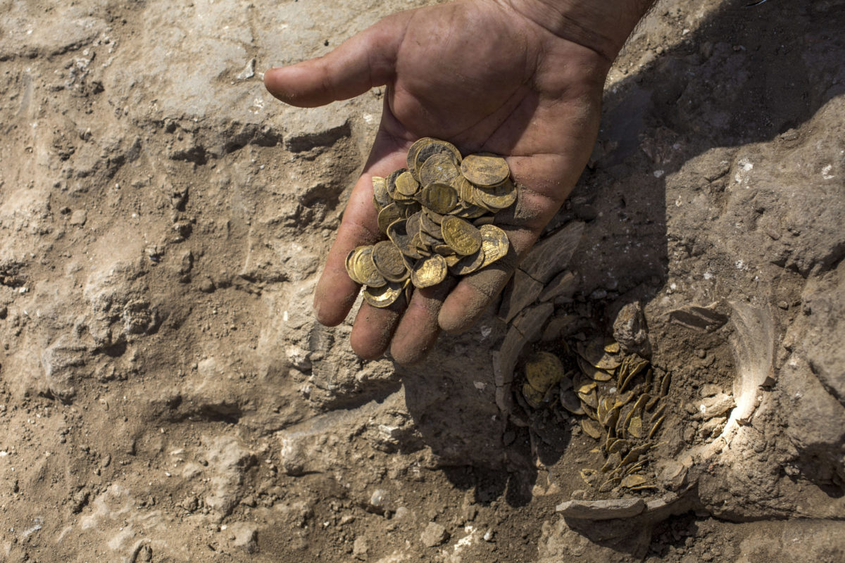 Israeli archaeologist Shahar Krispin displays gold coins that was discovered at an archeological site in central Israel, Tuesday, Aug 18, 2020. Israeli archaeologists have announced the discovery of a trove of early Islamic gold coins during recent salvage excavations near the central city of Yavn Tel Aviv. The collection of 425 complete gold coins, most dating to the Abbasid period around 1,100 years ago, is a "extremely rare" find. (AP Photo/Sipa Press, Heidi Levine, Pool)