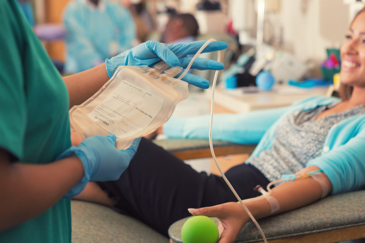 Phlebotomist preparing patient to donate blood in hospital lab