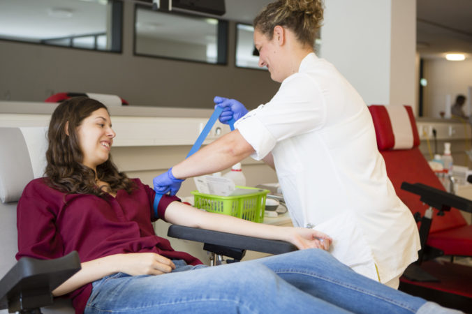 Young woman get prepared by a nurse for blood donation