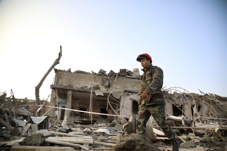 A soldier walks past a destroyed house in a residential area that was hit by rocket fire overnight by Armenian forces, early Saturday, Oct. 17, 2020, in Ganja, Azerbaijan's second largest city, near the border with Armenia. Azerbaijan has accused Armenia of striking its second-largest city with a ballistic missile that killed at least 13 civilians and wounded 50 others in a new escalation of their conflict over Nagorno-Karabakh.