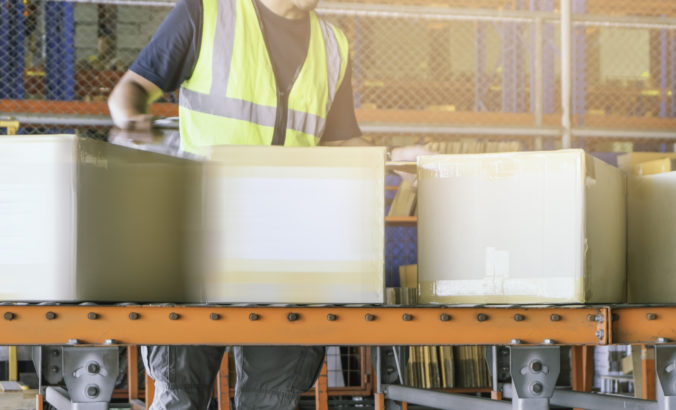 Worker is sorting package boxes on conveyor belt, cartons, cardboard boxes, delivering shipment parcels,