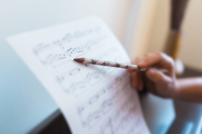 Horizontal detail of teacher explaining correct music lecture of piano score.