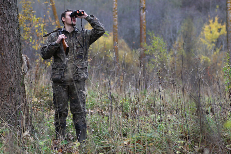 Man in camouflage and with guns in a forest belt on a spring hun