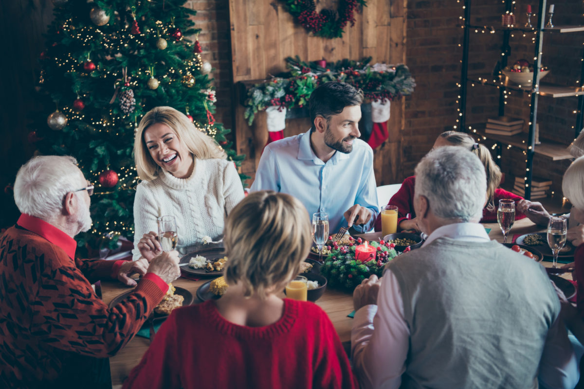 Photo of full family gathering sitting dinner table communicating chatting overjoyed x mas party multi generation in newyear decorated living room indoors