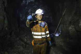 Miner in the mine. Well uniformed miner inside mine raising thumb