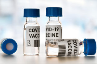 Coronavirus Covid 19 vaccine concept - small glass vials with blue caps on white table, closeup detail (own design - dummy bar code)
