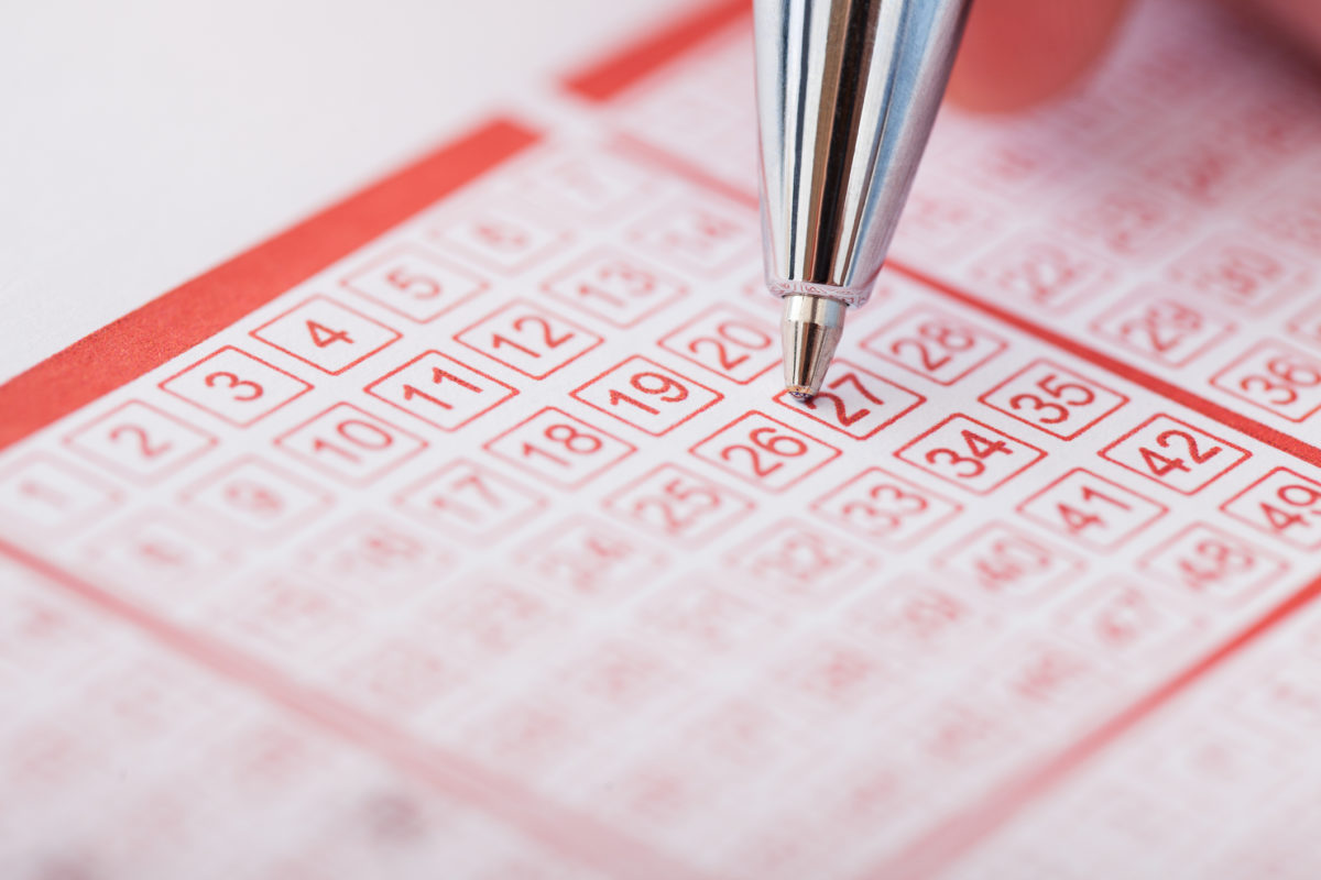 Person Holding Pen Over Lottery Ticket